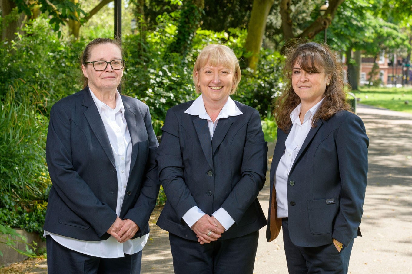 A team of funeral arrangers from JH Kenyon funeral directors stand together in a local park