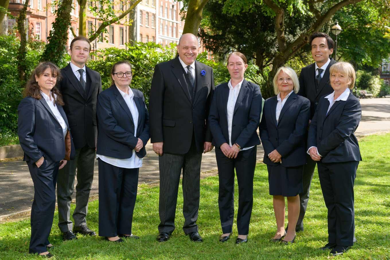 The team of funeral directors and funeral arrangers from JH Kenyon funeral directors stand together in a local park